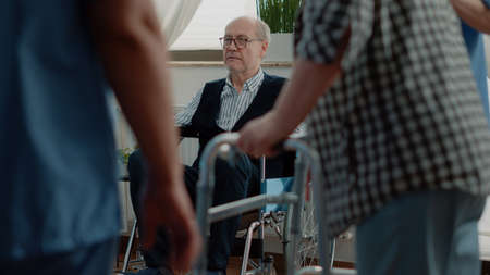 Old disabled man relaxing in nursting home room. Retired person with disability sitting in...