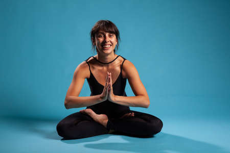 Portrait of smiling trainer standing in padmasana position during spiritual meditation working at healthy lifestyle. Active fit woman stretching body muscles during pilates workout. Sport conceptの写真素材