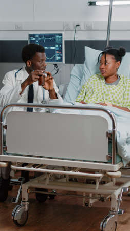 Medic holding bottle of pills to give to sick patient in bed. Man working as doctor giving flask...