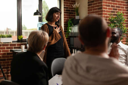 Impressed woman receiving applause from group of people at aa meeting program. Therapy session patients clapping hands and celebrating achievement, showing support to joyful person.の写真素材