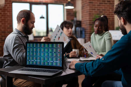 Diverse businesspeople discussing financial profit analyzing stock data during business meeting in...