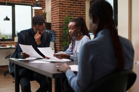Marketing agency team members reviewing accounting documentation and revenue statistics data....