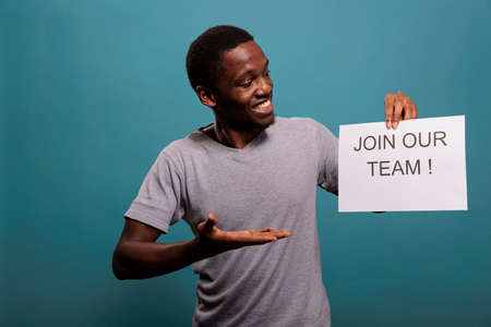 African american worker holding paper to make job offer in front of camera, hiring candidate for career opportunity. Human resources employee asking people to attend job interview.の写真素材