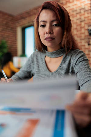 Entrepreneur woman analyzing management graphs while working at company project in startup office. Executive manager brainstorming marketing ideas planning new startegy, Business conceptの写真素材