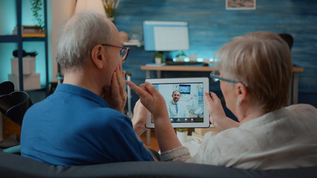 Aged man and woman talking to dentist on online video call, asking about toothache. Elder people using video teleconference to chat with orthodontist on digital tablet. Remote telemedicineの写真素材