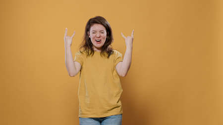 Rebel woman with positive attitude doing rock and roll hand gesture with tongue out wanting to party...