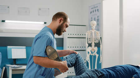 Health specialist doing physical therapy exercise with old man in osteopathy cabinet. Therapist...