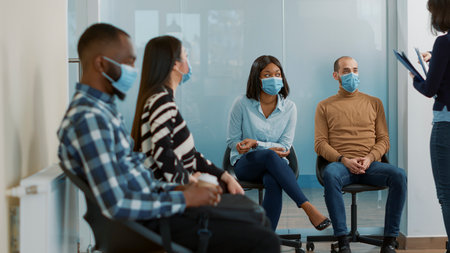 HR employee giving resume files to diverse group of candidates waiting in queue to attend job...
