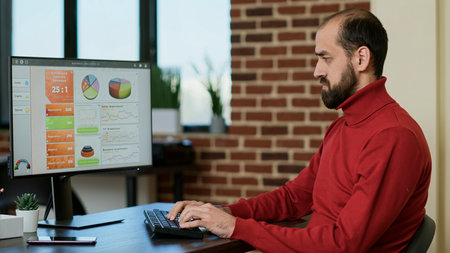 Male employee working on computer to develop sales profit, using financial information on charts,...