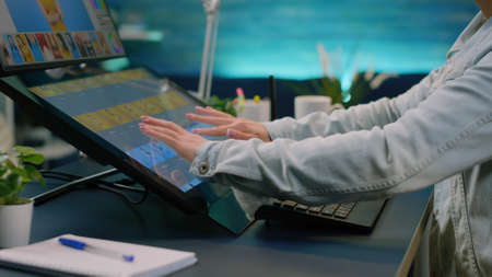 Close up of photographer hands using touch screen monitor on retouching software for pictures design...