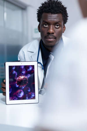 Hospital expert virologist showing symptoms of virus and effects of prescribed medication. Hospital doctor talking about virus mutations, disease evolution and health complications after recovery.の写真素材