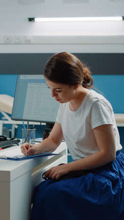 Caucasian patient signing checkup document for healthcare system after examination with doctor. Medic asking woman for signature on medical paper used for prescription treatment.の写真素材