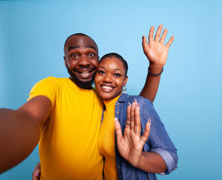 POV of cheerful people waving at camera and taking pictures in studio. Happy man and woman sharing...