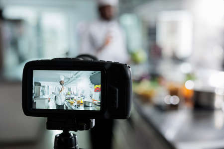 Close up camera recording gastronomy expert in restaurant kitchen filming culinary course while cooking delicious dish. Head chef vlogging preparing of gourmet food for gastronomic course on internet.の写真素材