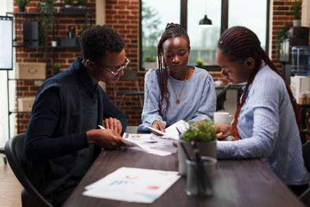 Management department employees analyzing accounting financial documentation. Business agency office workers reviewing marketing documents and startup strategy expenses while in modern interior.の写真素材