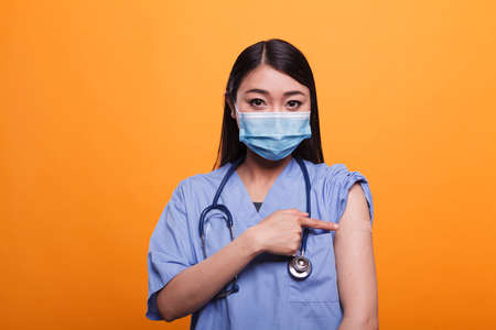 Responsible caregiver wearing bandage while encouraging people to immunise by getting anti-covid injection. Friendly healthcare nurse promoting vaccination against coronavirus epidemic.の写真素材