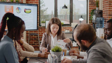 Diverse group of workmates discussing business strategy in startup office. Colleagues working on project planning and presentation for company development and growth. Brainstorming ideasの写真素材