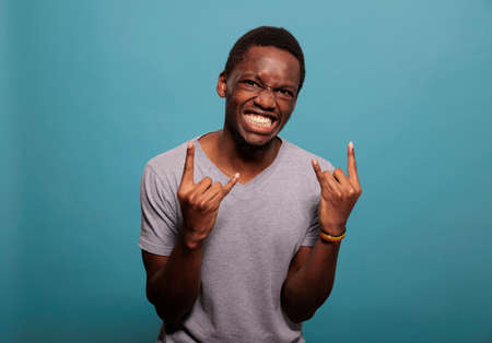 Funky person advertising rock and roll symbol with fingers in front of camera, expressing love for...