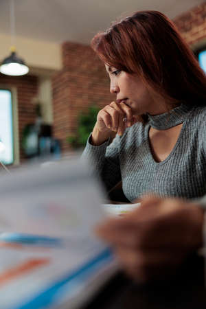 Businesswoman holding business papers checking management statistics while working at company strategy in startup office. Executive manager brainstorming ideas for partnership projectの写真素材