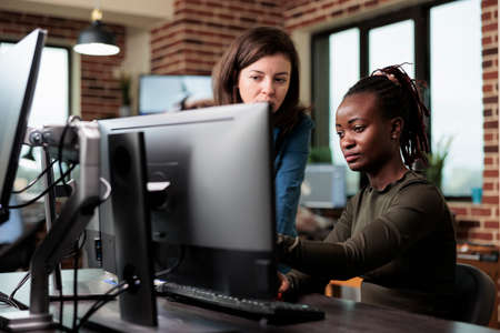 Creative company office workers sitting at desk in office workspace while discussing about graphics...