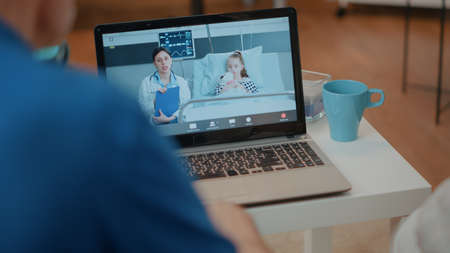 Worried grandparents using videoconference call on laptop to talk to medic and little girl in...