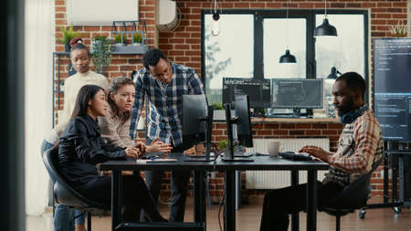 Junior developers collaborating on group project compiling algorithm asking senior programer for...