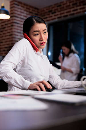 Confident financial advisor talking on modern touchscreen smartphone with finance department leader about accounting data. Business company employee on cellphone call with startup project manager.の写真素材