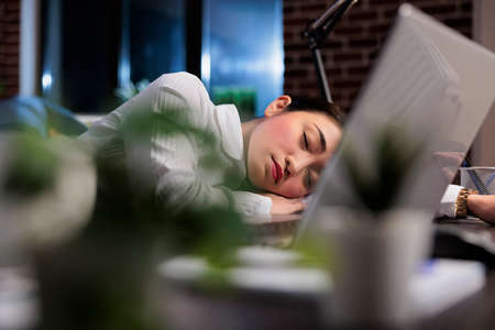Tired executive manager with burnout syndrome sleeping at work because of extreme fatigue. Exhausted financial accountant suffering from sleepiness after overtime working hours.の写真素材