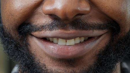 Macro shot of man moving his lips in front of camera and smiling, showing positive facial expression. Healthy person with natural skin showing candid smile, having short beard. Authentic emotions.の写真素材