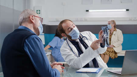 General practitioner analyzing radiography results in office, explaining x ray scan diagnosis to...