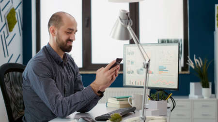 Financial assistant working on smartphone app with statistics, using moible phone to browse internet...