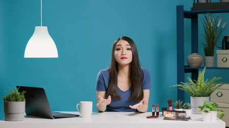 Content creator recording beauty vlog with cosmetics in studio, filming makeup tutorial and doing...