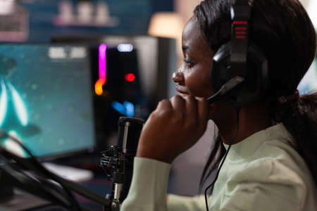 Cyber woman gamer talking into microphone during live streaming while playing online video games...