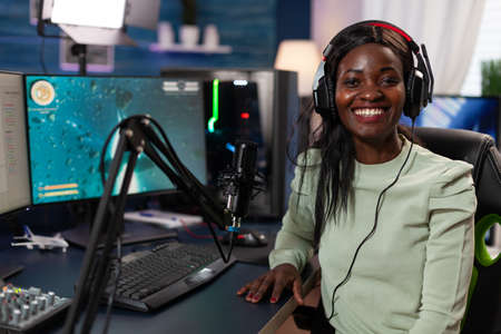 Portrait of concentrated pro gamer smiling at camera while playing space shooter videogames during...