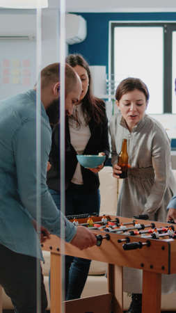 Frustrated man losing foosball game having fun after work at office. Woman beating person while...