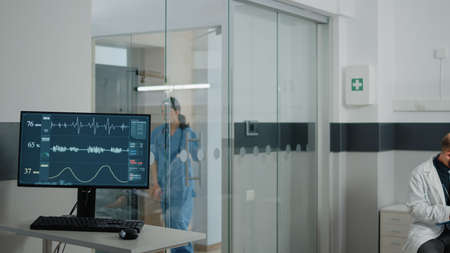 Heart rate monitor at clinic measuring pulse while doctor doing checkup with patient. Intensive care...