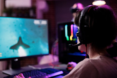 Happy woman streaming online multiplayer video games play on computer, enjoying shooting gameplay tournament. Female streamer playing action rpg game competition on pc monitor.の写真素材