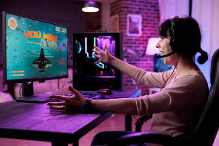 Young gamer celebrating video games championship win on online live stream, feeling happy at desk...