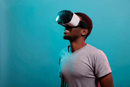 Modern guy using vr headset to play with 3d futuristic simulation in studio. Virtual reality goggles...