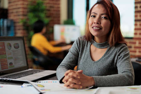 Portrait of smiling entrepreneur worker working at management project analyzing company graphs in...
