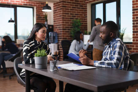 Asian woman arrived for interview sitting at desk in office while talking with business company...