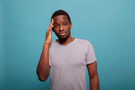 Stressed man dealing with headache and rubbing temples to stop pain, feeling unhappy and worried...