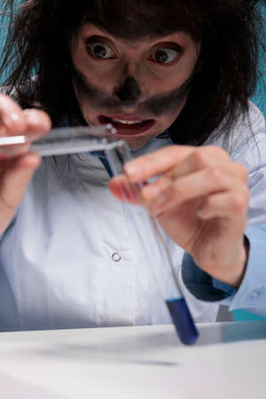 Close up of clumsy mad chemist mixing chemical substances to create new formula by using unknown compounds. Funny looking crazy scientist experimenting with toxic fluids resulted from lab explosionの写真素材