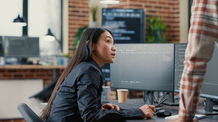 Database developer pointing pencil at computer screen with software compiling code explaining source...