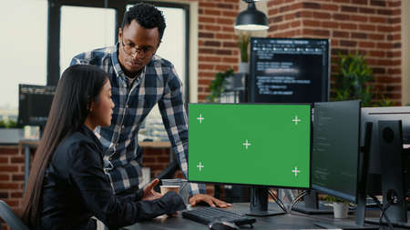 Mixed team of programmers analyzing source code looking at green screen chroma key mockup discussing algorithm. App developers working on online cloud computing in server room.の写真素材