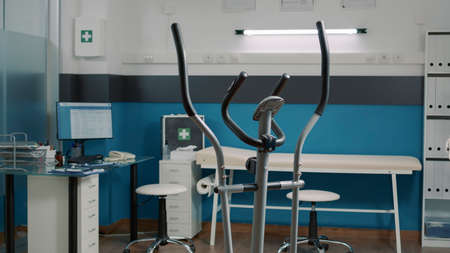 Empty doctor office with physical therapy stationary bicycle and heart rate monitor to measure heartbeat. Alternative medicine cabinet to do osteopathy consultation and exam. Rehabilitationの写真素材