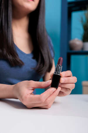 Close up of artist vlogger hand holding lipstick while recording make up review for vlogging channel in studio. Blogger content creator filming cosmetics tutorial advertising productの写真素材
