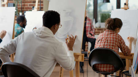 African american student drawing contemporary sketch in art class program, using pencil and canvas...