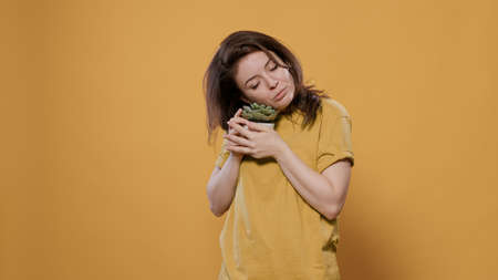 Portrait of woman being affectionate with succulent plant showing love for house plants in studio....