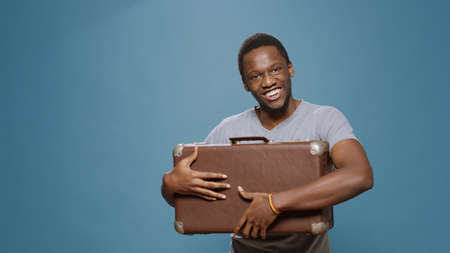 Young adult carrying voyage briefcase for tourist departure, getting ready to leave on vacation trip. Person with suitcase going on adventure journey abroad with luggage for cityscape holiday.の写真素材